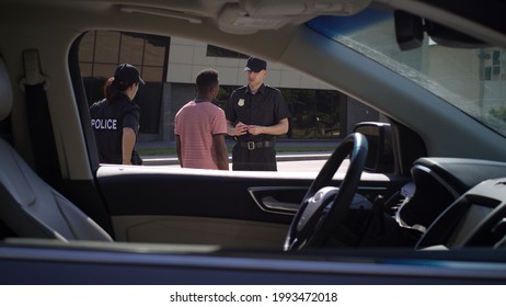 Diverse Police Officers Checking Documents Of Black Driver