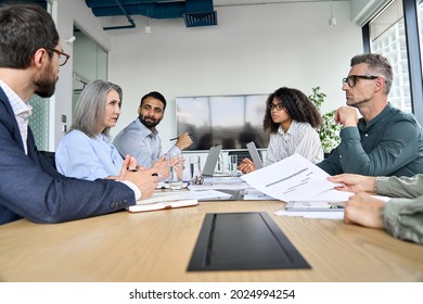 Diverse professional executive business team people discuss project sitting at meeting table in board room. Multiethnic company managers brainstorm financial plan working together in boardroom.