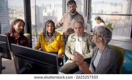 Diverse professional team analyzing complex business data while collaborating near computer, city skyline visible through expansive office window during strategic meeting