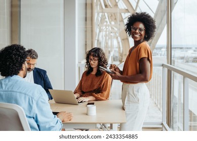 Diverse professionals in a boardroom engage in a lively discussion. A confident businesswoman leads the meeting while colleagues take notes.  - Powered by Shutterstock