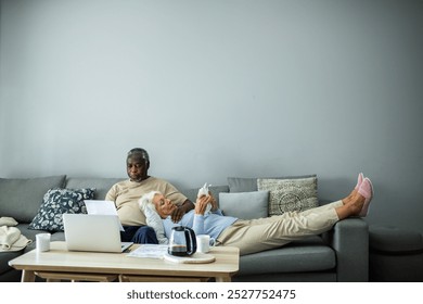 Diverse senior couple reading bills on the couch at home - Powered by Shutterstock