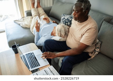 Diverse senior couple reading bills on the couch at home - Powered by Shutterstock