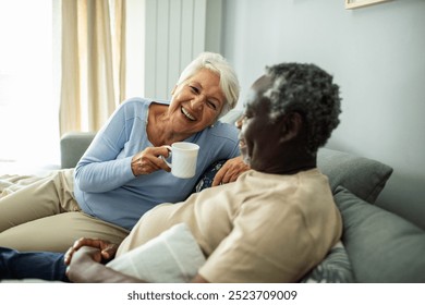 Diverse senior couple relaxing together on the couch at home - Powered by Shutterstock