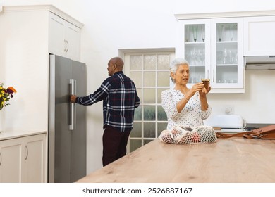 Diverse senior couple unpacking groceries in kitchen. Lifestyle, retirement, senior lifestyle, shopping, togetherness and domestic life, unaltered. - Powered by Shutterstock