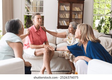 Diverse senior female friends having serious conversation about emotions. retirement, friendship, senior living, happiness, unaltered, living room with cozy decor and soft lighting - Powered by Shutterstock