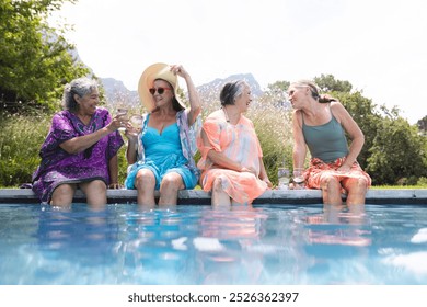 Diverse senior female friends laughing outdoors, by pool. Biracial woman in purple, Caucasian in blue, Asian in orange, and another Caucasian with green background, sharing stories, unaltered - Powered by Shutterstock