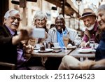 Diverse senior tourist friends taking selfie in outdoor city cafe