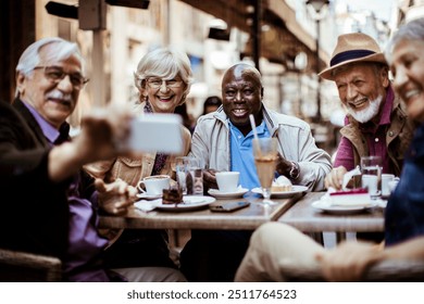 Diverse senior tourist friends taking selfie in outdoor city cafe - Powered by Shutterstock