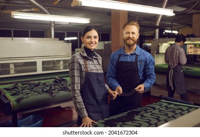 Diverse shoemaker team working on fabric shoes creation at factory workshop. Two smiling male and female designer looking at camera standing at desk with textile material footwear pieces - Powered by Shutterstock