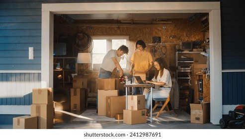 Diverse Small Business Partners Working in Home Garage. Hispanic Female Manager Filling Online Orders On Laptop Computer. Two Caucasian Male Friends Packing Products In Boxes For Delivery To Clients. - Powered by Shutterstock