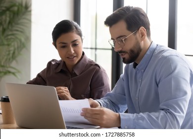 Diverse Smiling Businessman And Businesswoman Reading Finance Report Talking Looking At Document. Indian Woman And Male Manager Discuss And Looking Decision In Negotiation. Teamwork At Workplace.