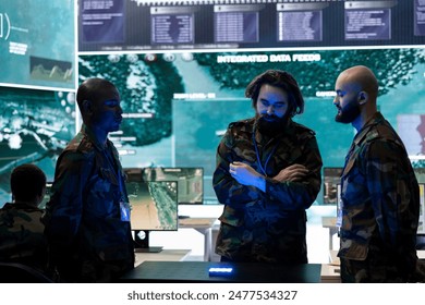 Diverse soldiers analyzing satellite images on a 3d hologram to discuss operations plan in command post, operating with high tech gear. Recruits using 3d projection for new defense mission. - Powered by Shutterstock