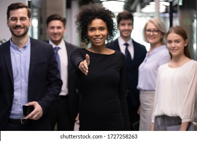 Diverse staff on background focus on African businesswoman leader outreached hand for handshake, congratulate applicant with new vacancy, greeting client express gratitude for successful negotiations