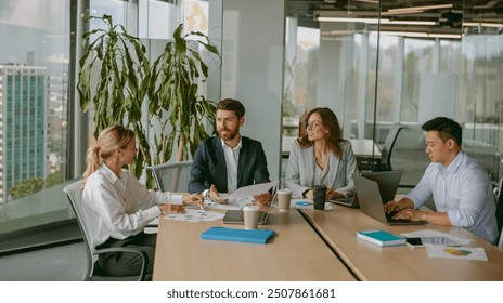 A diverse, talented team collaborates effectively in a bright office space during a business meeting - Powered by Shutterstock