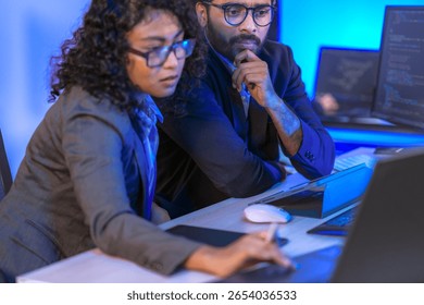 Diverse team of AI developers collaborating in a modern office. Indian male leading a discussion with Asian and Hispanic female colleagues on a machine learning project.