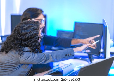 Diverse team of AI developers collaborating in a modern office. Indian male leading a discussion with Asian and Hispanic female colleagues on a machine learning project.
