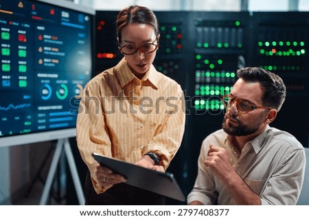 Diverse it team analyzing important system analytics and data visualization on a tablet in a modern server room