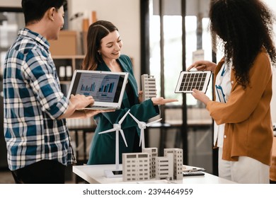 Diverse team with Asian man, African American woman, Caucasian woman discussing a clean energy city planning project with building models and solar panels. - Powered by Shutterstock