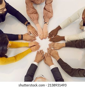 Diverse team of business people sitting in office and having a meeting. Human hands of different colours on white table, top view from above. Square background. Community, diversity, teamwork concepts
