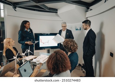 Diverse team of businesspeople is discussing in a meeting about renewable energies, analyzing data and planning future investments - Powered by Shutterstock