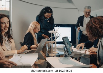 Diverse team of businesspeople are having a meeting about renewable energy, smiling and looking happy - Powered by Shutterstock