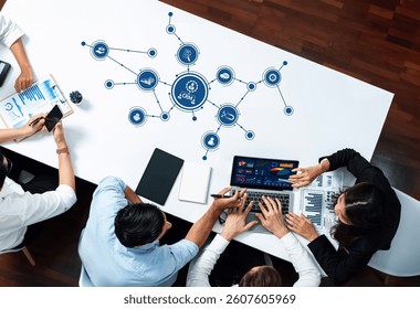A diverse team collaborates in a modern office setting, analyzing data and discussing business strategies with a laptop and documents focused on CRM insights and visualizations. Amity