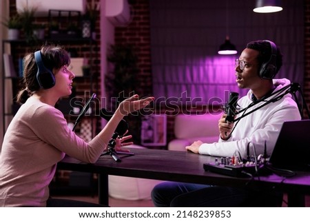 Diverse team of content creators streaming podcast show with recording and sound equipment. Man and woman meeting in studio to broadcast live discussion online, internet channel vlog.