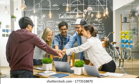 Diverse Team Of Creative Developers Make Building Successful Partnership Gesture With Teir Hands. Happy Succesful Young People Stylishly Dressed In The Trendy Office Environment.