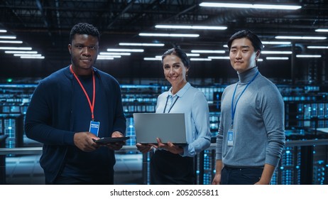 Diverse Team Of Data Center System Administrators And IT Specialists Use Laptop And Tablet Computers, Smiling On Camera. IT Engineers Work On Cyber Security Protection In Cloud Computing Server Farm.