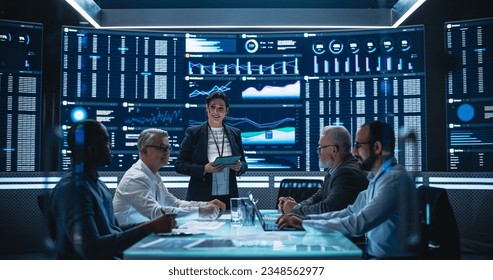 Diverse Team Of Data Scientists and Software Developers Discussing Reports in Monitoring Room with Analytics Feed on Big Digital Screen. Female Leading Artificial Intelligence Company Board Meeting