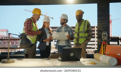 Diverse team of engineers and construction workers having a meeting, examining blueprints and discussing a project on a construction site