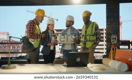 Diverse team of engineers and construction workers having a meeting, examining blueprints and discussing a project on a construction site