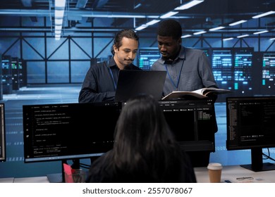 Diverse team of engineers in data center looking for firewall misconfigurations affecting servers. Multiracial workers in server room check systems bottlenecks leading to sluggish data transfer rates - Powered by Shutterstock