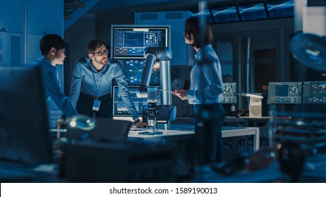 Diverse Team of Engineers with Laptop and a Tablet Analyse and Discuss How a Futuristic Robotic Arm Works and Moves a Metal Object. They are in a High Tech Research Laboratory with Modern Equipment. - Shutterstock ID 1589190013