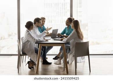 Diverse team of hospital doctors meeting at table, talking on cooperation, teamwork in hospital, discussing difficult patients case, listening to speaking medical expert. Wide shot - Powered by Shutterstock