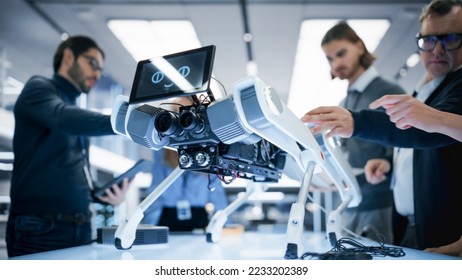 Diverse Team of Industrial Robotics Specialists Gathered Around a Table With a Mobile Robot. Scientists Use Tablet and Laptop Computers to Program the Automated AI Robotic Dog. - Powered by Shutterstock