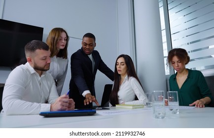 Diverse team of managers gathering around table and discussing company progress, Black man showing something on tablet. Employees brainstorming at meeting. Concept of business