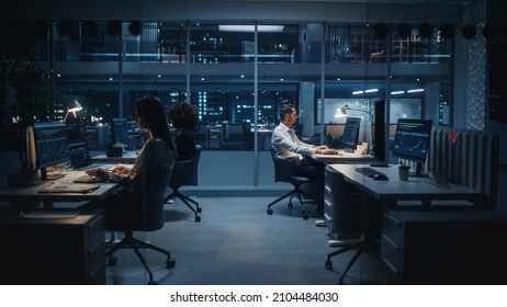 Diverse Team of Managers Working on Computers Behind Desks in Big City Office in the Evening. Colleagues Work,  Creating Financial Reports, Play on Stock Market, Plan Investment Strategy.