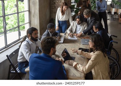 Diverse team members engage in a collaborative meeting in a bright, modern office space, emphasizing inclusivity and teamwork. - Powered by Shutterstock