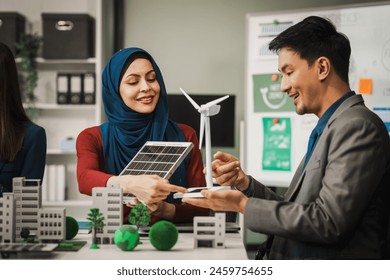 Diverse team, middle-aged Asian businessman, Caucasian young businesswoman, Muslim hijab-wearing businesswoman, meets in boardroom to discuss a wind turbine project for sustainable energy solutions. - Powered by Shutterstock