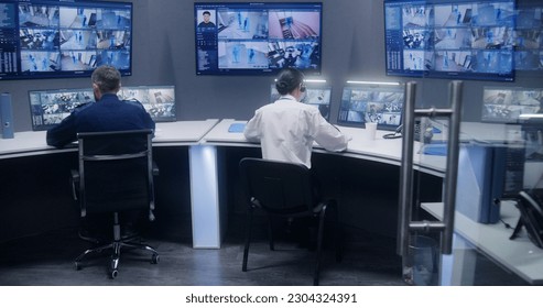 Diverse team of officers watch CCTV cameras with AI facial recognition. Employees work in security control center. Computer monitors and big digital screens showing surveillance cameras video footage. - Shutterstock ID 2304324391