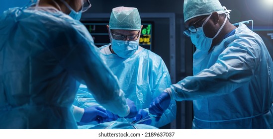 Diverse team of professional medical surgeons perform surgery in the operating room using high-tech equipment. Doctors work to save a patient in a modern hospital. Medicine, technology and healthcare. - Powered by Shutterstock