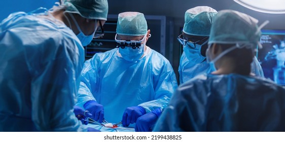 Diverse Team Of Professional Medical Surgeons Perform Surgery In The Operating Room Using High-tech Equipment. Doctors Work To Save A Patient In A Modern Hospital. Medicine, Technology And Healthcare.