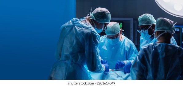 Diverse Team Of Professional Medical Surgeons Perform Surgery In The Operating Room Using High-tech Equipment. Doctors Work To Save A Patient In A Modern Hospital. Medicine, Technology And Healthcare.