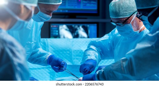 Diverse Team Of Professional Medical Surgeons Perform Surgery In The Operating Room Using High-tech Equipment. Doctors Work To Save A Patient In A Modern Hospital. Medicine, Technology And Healthcare.