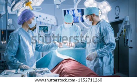 Diverse Team of Professional surgeon,  Assistants and Nurses Performing Invasive Surgery on a Patient in the Hospital Operating Room. Real Modern Hospital with Authentic Equipment.