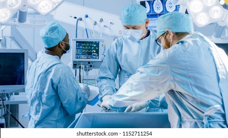 Diverse Team Of Professional Surgeons Performing Invasive Surgery On A Patient In The Hospital Operating Room. Nurse Hands Out Instruments To Surgeon,  Anesthesiologist Monitors Vitals.