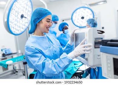 Diverse Team Of Professional Surgeons Performing Invasive Surgery On A Patient In The Hospital Operating Room. Nurse Hands Out Instruments To Surgeon, Anesthesiologist Monitors Vitals.