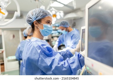 Diverse Team of Professional Surgeons Performing Invasive Surgery on a Patient in the Hospital Operating Room. Nurse Hands Out Instruments to surgeon, Anesthesiologist Monitors Vitals. - Powered by Shutterstock