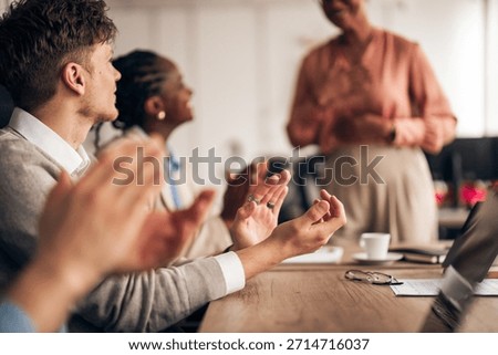 A diverse team of professionals clapping during a presentation, showcasing collaboration in a workplace.
